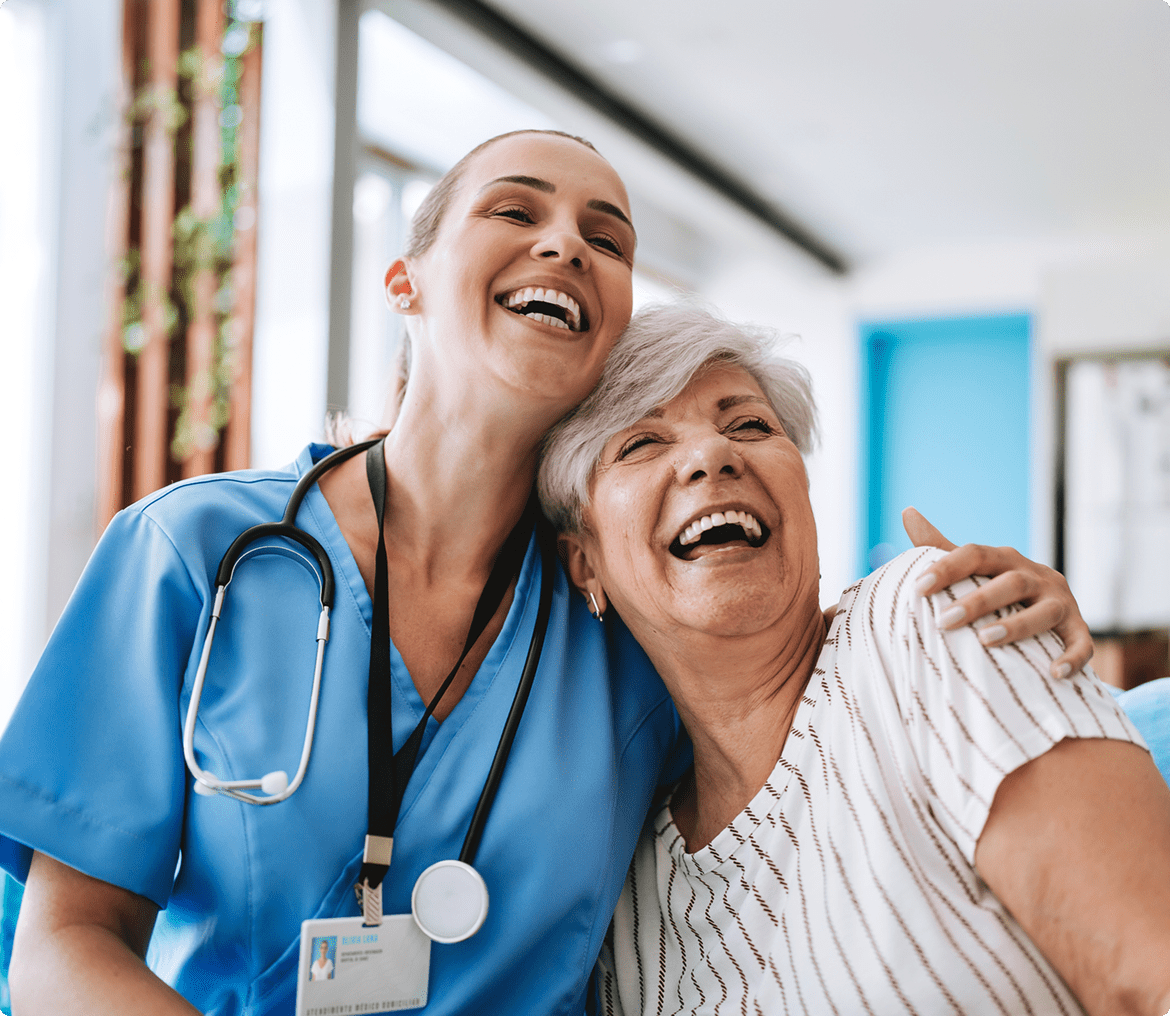 Elderly woman laughing with healthcare worker.