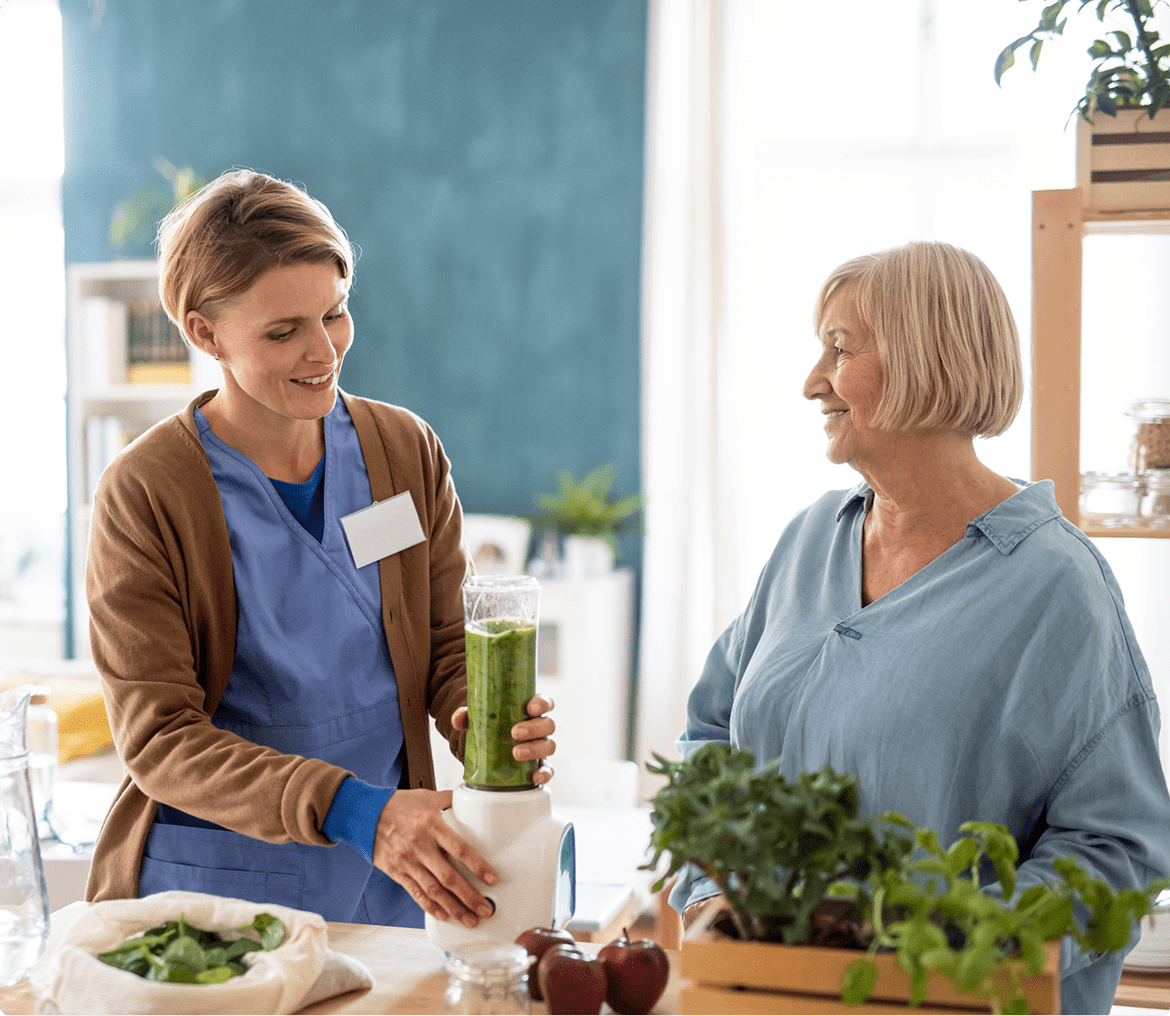 Smiling women making smoothie together at home