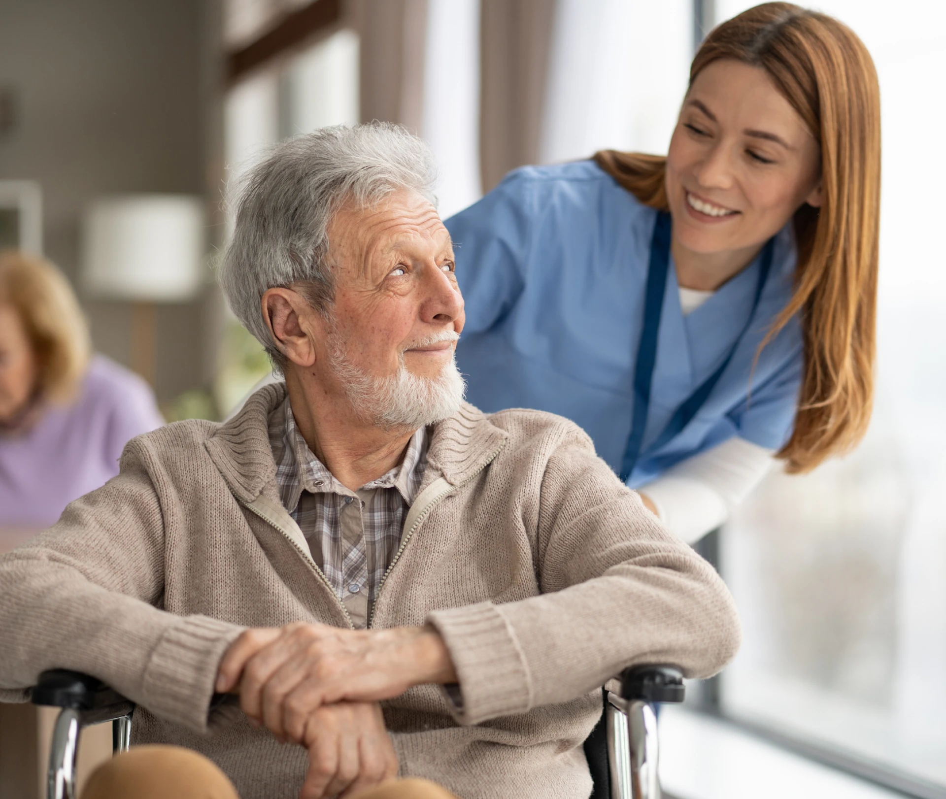 Nurse assisting elderly man in cozy room.