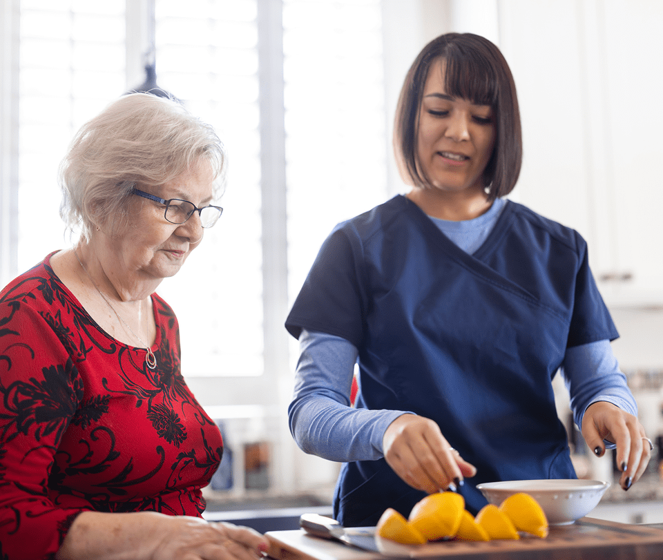Healthcare worker slicing oranges for older lady