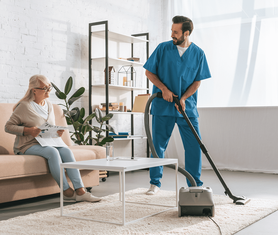 Caregiver cleaning living room for elderly woman