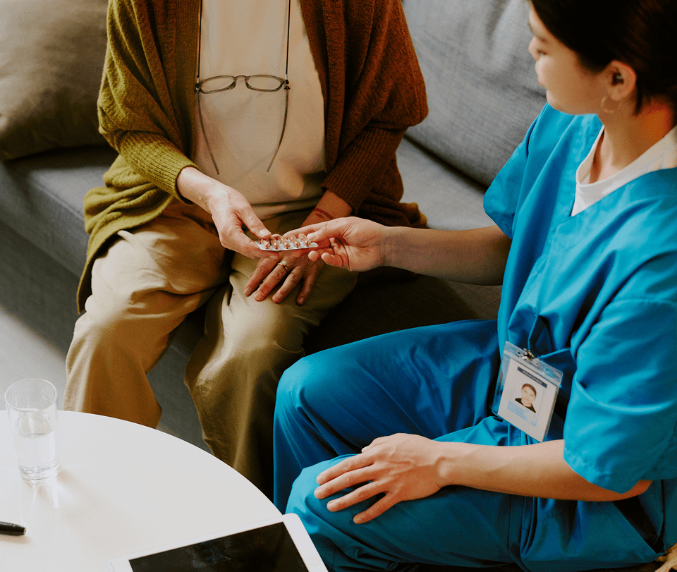 Nurse giving pills to elderly woman